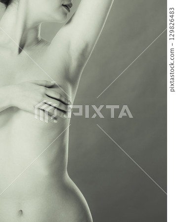 woman examining her breasts for breast cancer woman examining her breasts for breast cancer 129826483