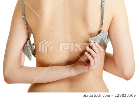 Attractive slim woman taking off grey bra 129826509