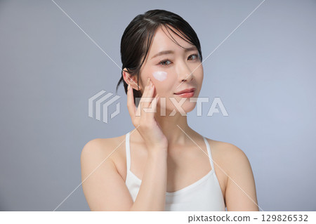 Beauty image: Young woman applying cream 129826532