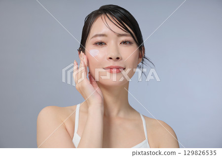 Beauty image: Young woman applying cream 129826535