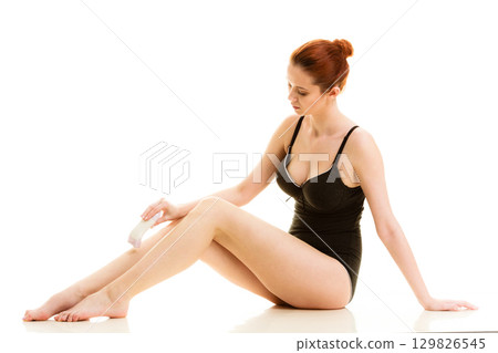 Woman shaving her legs with electric razor 129826545