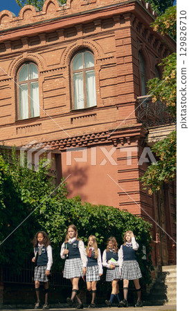 Group of schoolgirls walking together after class in confident mood 129826710
