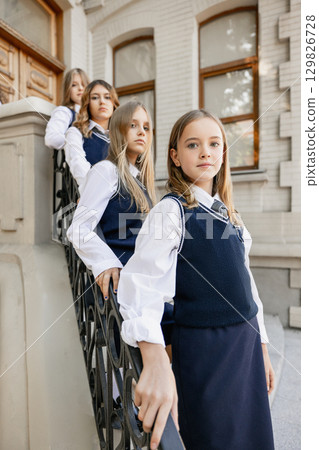 Teenage girls in line on stairs with serious expression symbolizing unity and feminism Teenage girls in line on stairs with serious expression symbolizing unity and feminism 129826728
