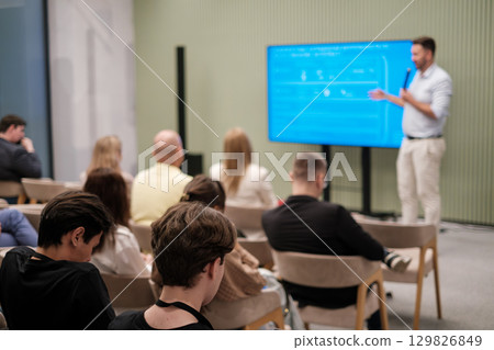 Speaker addressing diverse audience during educational seminar in modern conference space Speaker addressing diverse audience during educational seminar in modern conference space 129826849