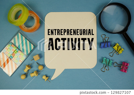 Entrepreneurial Activity text with magnifying glass on blue background 129827107