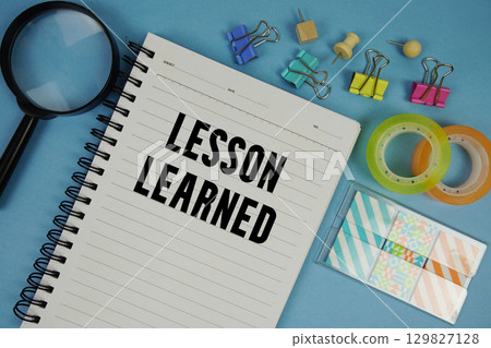 Lesson Learned text with magnifying glass on blue background 129827128
