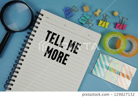 Tell Me More text with magnifying glass on blue background 129827132