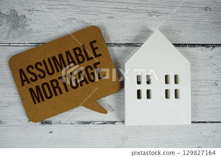 Assumable Mortgage text with house models on wooden background 129827164