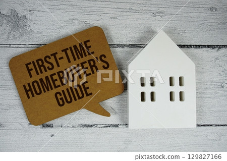First-time Homebuyer's Guide text with house models on wooden background 129827166