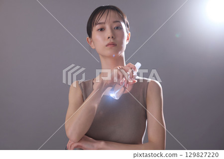 Beauty image: A young woman holding lotion 129827220