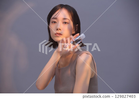 Beauty image: Young woman holding lotion 129827403