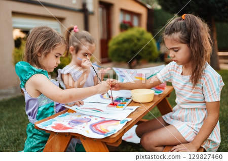 Three little girls painting in the backyard garden Three little girls painting in the backyard garden 129827460
