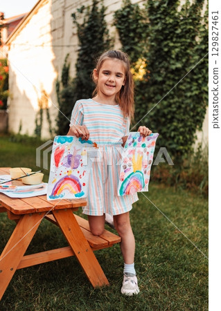 Little girl showing her drawings in the garden 129827461
