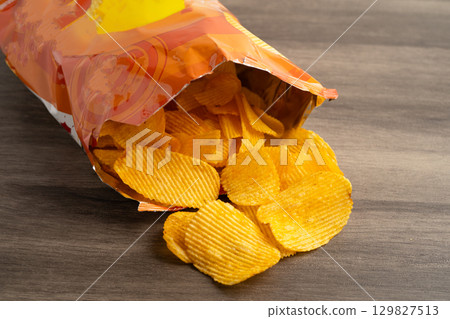 Potato chips, delicious BBQ seasoning spicy for crips, thin slice deep fried snack fast food in open bag. Potato chips, delicious BBQ seasoning spicy for crips, thin slice deep fried snack fast food in open bag. 129827513