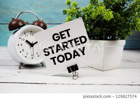 Get Started Today text written on paper card with alarm clock on wooden background Get Started Today text written on paper card with alarm clock on wooden background 129827574