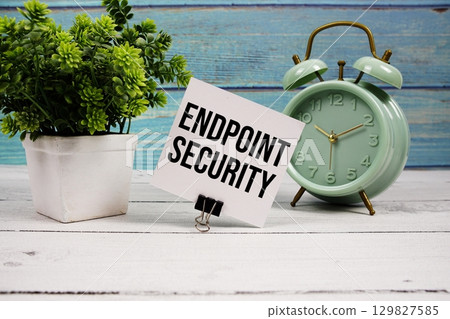 Endpoint Security text written on paper card with alarm clock on wooden background 129827585