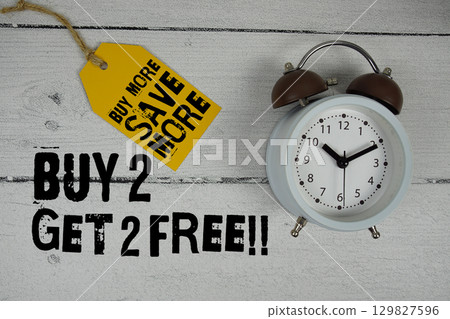 Buy 2 Get 2 Free!!! Shop Now text with alarm clock on wooden background 129827596