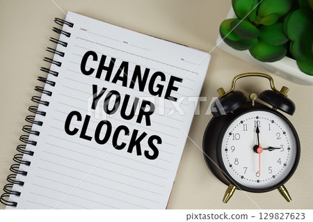 Change Your Clocks text written on notepad with alarm clock 129827623