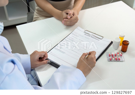 Healthcare Consultation. Doctor reviewing health summary with patient during medical appointment. 129827697