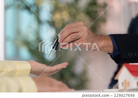 Home Keys Exchange. A real estate agent handing over keys to a new homeowner. Home Keys Exchange. A real estate agent handing over keys to a new homeowner. 129827698