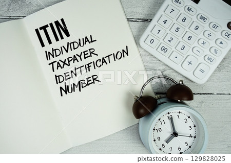 ITIN Individual Taxpayer Identification Number text on paper notebook page with alarm clock and calculator on wooden background ITIN Individual Taxpayer Identification Number text on paper notebook page with alarm clock and calculator on wooden background 129828025