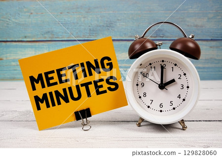 Meeting Minutes text written on paper card with alarm clock on wooden background 129828060