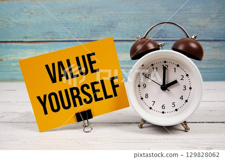Value Yourself text written on paper card with alarm clock on wooden background 129828062