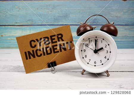 Cyber Incident text written on paper card with alarm clock on wooden background Cyber Incident text written on paper card with alarm clock on wooden background 129828068