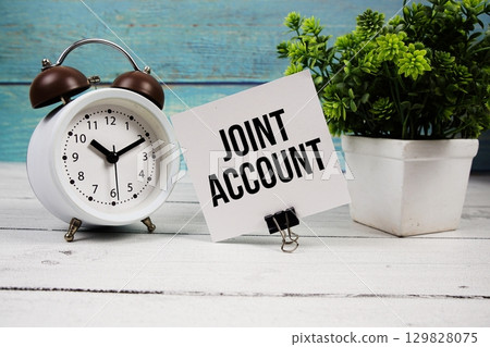 Joint Account text written on paper card with alarm clock on wooden background Joint Account text written on paper card with alarm clock on wooden background 129828075