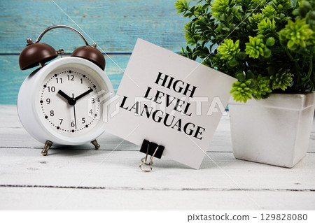 High-Level Language text written on paper card with alarm clock on wooden background 129828080