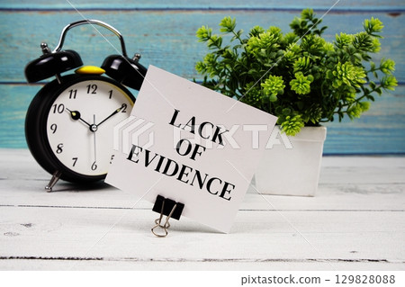 Lack Of Evidence text written on paper card with alarm clock on wooden background Lack Of Evidence text written on paper card with alarm clock on wooden background 129828088