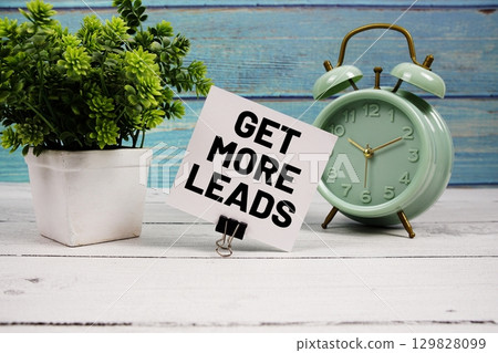 Get More Leads text written on paper card with alarm clock on wooden background 129828099