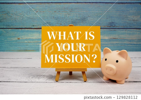 What is your mission? text written on paper card with piggy bank on wooden background 129828112