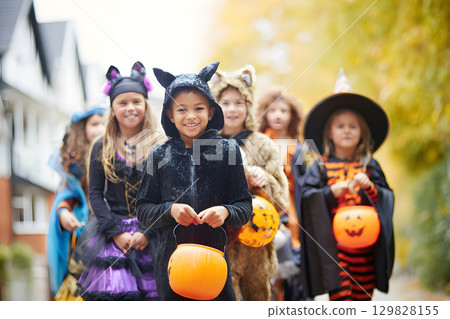 Children dressed up for Halloween. Portrait of a smiling girl holding candy 129828155