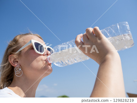 Tourist enjoying refreshing water on hot summer day, promoting hydration and healthy lifestyle Tourist enjoying refreshing water on hot summer day, promoting hydration and healthy lifestyle 129828219