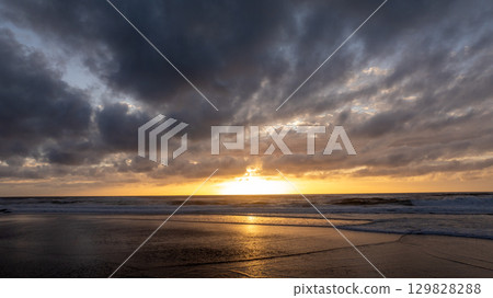 Golden sunset illuminating the shore of praia grande beach in Sintra, Portugal, creating a scenic seascape Golden sunset illuminating the shore of praia grande beach in Sintra, Portugal, creating a scenic seascape 129828288