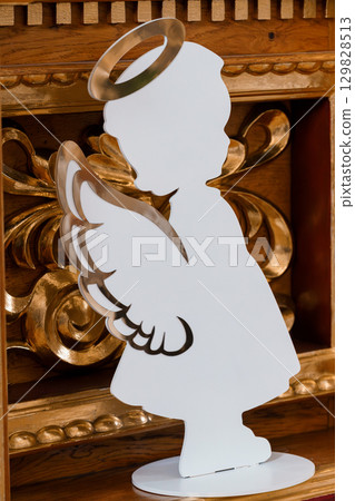 Elegant White Angel Silhouette with Halo and Wings Against Ornate Antique Wood Furniture Backdrop, Vintage Style 129828513