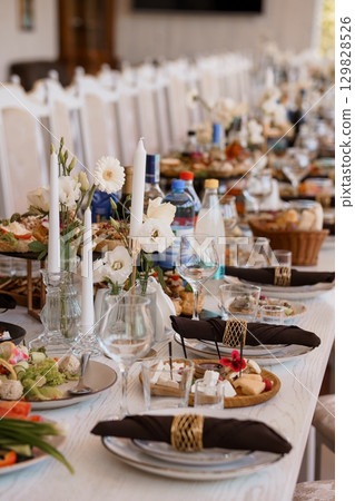Elegant Wedding Table Setting with Floral Centerpieces, White Linens, and Feast, Luxury Celebration, Fine Dining, Rustic Decor, Bright Daylight. Elegant Wedding Table Setting with Floral Centerpieces, White Linens, and Feast, Luxury Celebration, Fine Dining, Rustic Decor, Bright Daylight. 129828526