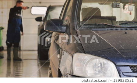 Car wash worker cleaning vehicles in a garage Car wash worker cleaning vehicles in a garage 129828551