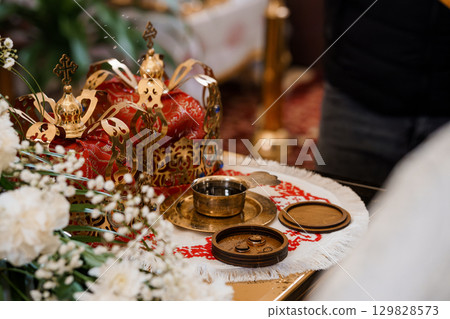 Orthodox Wedding Ceremony Detail: Golden Crosses, Red Velvet Cloth, and Symbolic Rings on Altar. Spiritual Ritual, Religion, White Flowers Orthodox Wedding Ceremony Detail: Golden Crosses, Red Velvet Cloth, and Symbolic Rings on Altar. Spiritual Ritual, Religion, White Flowers 129828573