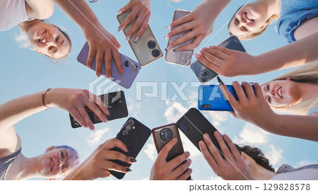 Joyful group of students forming a circle with their smartphones and having a great time together Joyful group of students forming a circle with their smartphones and having a great time together 129828578