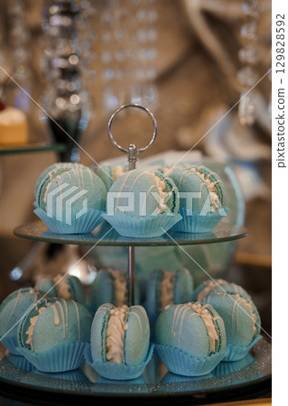 Turquoise Macarons Displayed on Elegant Tiered Stand, Wedding Dessert Table, Silver Accents, Luxury Confectionery, Pastel Colors, Close-Up Shot 129828592