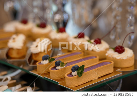 Exquisite Tartlets Display. Delicate Pastry Selection for Events. Cream, Cherry, Blueberry, Glassware, Luxury, Wedding, Dessert Table, Bokeh, Soft Focus. Exquisite Tartlets Display. Delicate Pastry Selection for Events. Cream, Cherry, Blueberry, Glassware, Luxury, Wedding, Dessert Table, Bokeh, Soft Focus. 129828595