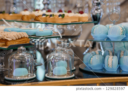 Luxurious Blue Pastel Dessert Buffet Display Featuring Macarons, Cakes, and Pastries in Elegant Silver Stands, Festive Celebration, Soft Focus Luxurious Blue Pastel Dessert Buffet Display Featuring Macarons, Cakes, and Pastries in Elegant Silver Stands, Festive Celebration, Soft Focus 129828597