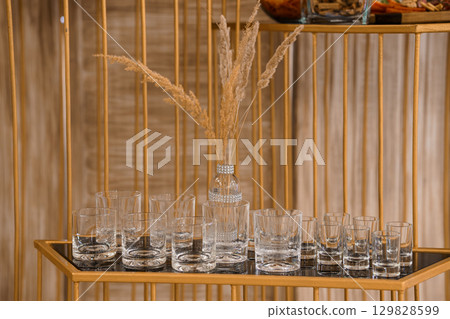 Elegant Golden Bar Cart Display with Crystal Glasses and Pampas Grass: Rustic Chic Home Decor and Entertaining Setup 129828599