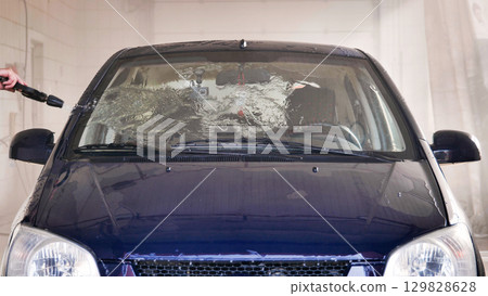 Car wash worker cleaning windshield with high pressure water jet Car wash worker cleaning windshield with high pressure water jet 129828628