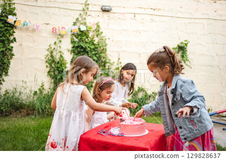 Children celebrate with a joyful cake cutting moment 129828637