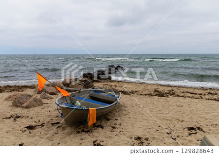 Grey sky is above the sea, boat stand on the beach. Grey sky is above the sea, boat stand on the beach. 129828643