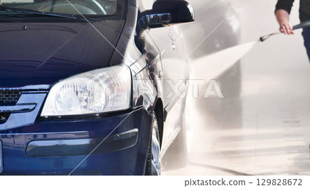 Car wash worker cleaning vehicle with high pressure water jet Car wash worker cleaning vehicle with high pressure water jet 129828672