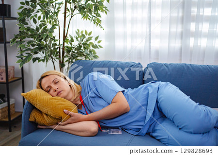 Exhausted Female Doctor Sleeping on Couch After Long Shift at Hospital 129828693